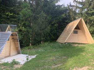 zwei hölzerne Unterstände auf einem Feld mit Bäumen in der Unterkunft Hillside Bio Glamping in Prebold