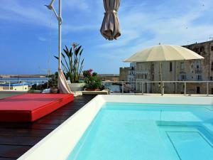 a swimming pool on top of a building with an umbrella at AL CONSOLE LUXURY SUITE in Monopoli