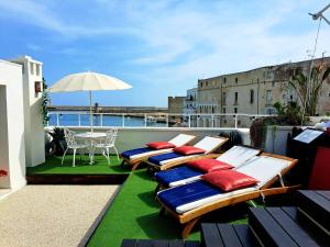 eine Reihe von Liegen auf einem Balkon mit einem Tisch in der Unterkunft AL CONSOLE LUXURY SUITE in Monopoli