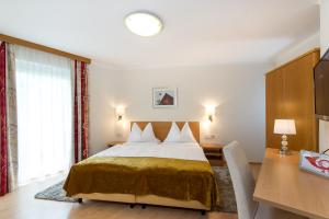 a hotel room with a bed and a desk and a bed at Gästehaus Wrann in Velden am Wörthersee