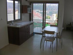 uma cozinha com um lavatório, uma mesa e cadeiras em ROSEHILLS em Kefar Weradim