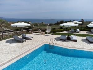 a swimming pool with chairs and umbrellas next to at Tramonto Suites in Xi