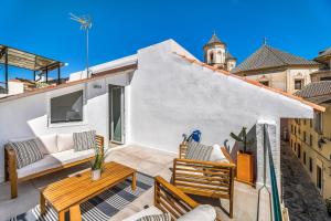 eine Terrasse mit Gartenmöbeln und einem TV auf einem Gebäude in der Unterkunft Urban Rose , Superb private House in historical center, with sunny rooftop in Málaga