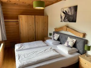 Schlafzimmer mit einem Bett mit weißer Bettwäsche und Kissen in der Unterkunft Hotel Gamshof in Kitzbühel
