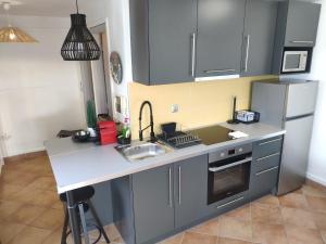 a kitchen with gray cabinets and a sink and a refrigerator at #Roof(pool)garden Private in Pikérmion
