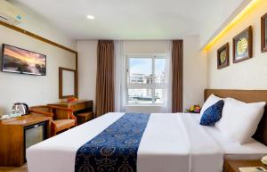 Cette chambre comprend un lit, un bureau et une fenêtre. dans l'établissement Saphia Hotel Nha Trang, à Nha Trang