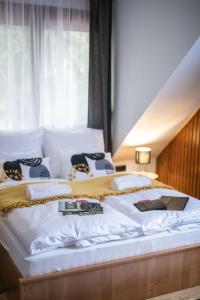 uma cama grande com lençóis brancos e almofadas em 4 Évszak Völgyhotel em Mátrafüred