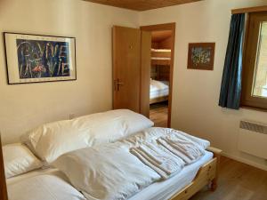 Una habitación con una cama con sábanas blancas. en Haus Tgamotsch***- Ferienwohnung in Valbella, en Valbella