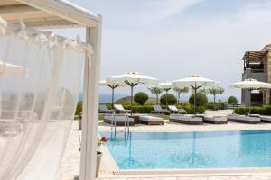 a pool with chairs and umbrellas next to a building at Tramonto Suites in Xi