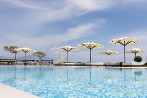 a swimming pool with chairs and umbrellas at Tramonto Suites in Xi +29 photos