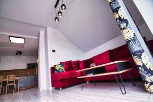 a living room with a red couch and a kitchen at Blue Sky - Apartamenty Zator in Zator