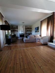 a living room with white furniture and a wooden floor at Villa Eleonas in Skala Kallirakhis
