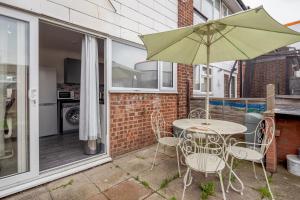 a patio with a table and chairs and an umbrella at Tms Lovely 3 Bed House-Tilbury-Free parking in Tilbury
