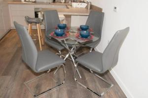 una mesa de cristal con 4 sillas y cuencos azules. en TMS Beautiful 2BR Apartment! Ensuite! Lakeside, en West Thurrock
