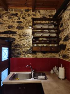 eine Küche mit einem Waschbecken und einer Steinmauer in der Unterkunft Grandma Agatha & Virginia's stonehouse in Kefálion