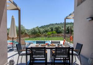 een terras met een tafel en stoelen en een zwembad bij VILLA ALKISTIS in Lefkada