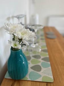 a green vase with white flowers on a table at Penwyn Bed and Breakfast in Looe