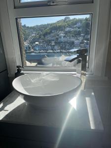 a bathroom with a large window and a white tub at Penwyn Bed and Breakfast in Looe