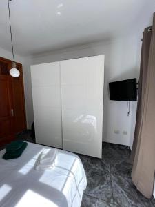 a bedroom with a white bed and a tv at Pico Lomito House in Moya