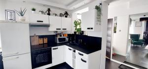 a kitchen with white cabinets and black counter tops at Apartamenty Magvel in Szczecin