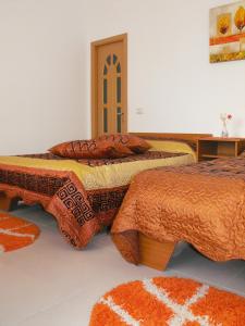 two beds in a room with orange comforters and pillows at Casa Rustica Apart & Rooms in Cîmpineanca