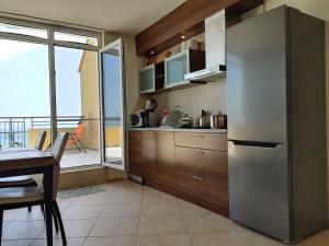 a kitchen with a stainless steel refrigerator and a table at AKB Apartment Sea View in Aheloy