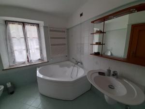 a white bathroom with a tub and a sink at San Marcello Residence in Feltre +25 photos