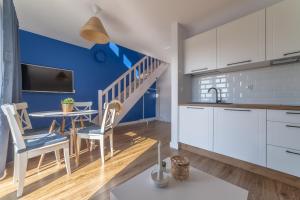 a kitchen with white cabinets and a table with chairs at Apartamenty Białe Piaski in Jastarnia