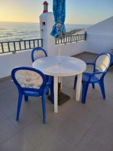 mesa y 2 sillas con sombrilla y faro en Beach House Above the Ocean AA3, en Ericeira