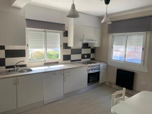 a kitchen with white cabinets and black and white tiles at Apt Sueiras in Burela de Cabo