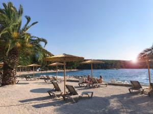 a group of people sitting on a beach with chairs and umbrellas at Apartment Adriana in Supetar