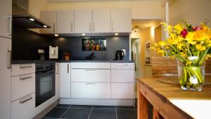 a kitchen with white cabinets and a vase of flowers at Waldidylle in Küsten