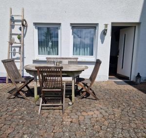 a wooden table with four chairs and a table and a building at Ferienwohnung am sonnigen Haimberg in Fulda