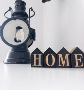 a black lamp with the word home next to a house sign at Apartament nad Jeziorem in Olecko