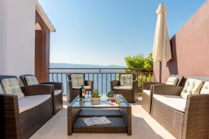 Un patio con sillas, una mesa y una sombrilla. en Apartmani Villa Bose, en Celina