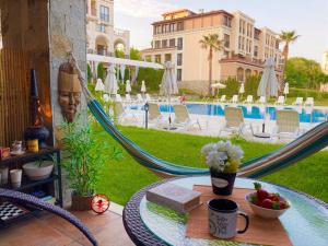 a patio with a table and hammocks and a pool at art STUDIO in Green Live beach resort - at ground floоr with Terrace and green patio just infront ot the Pool in Sozopol