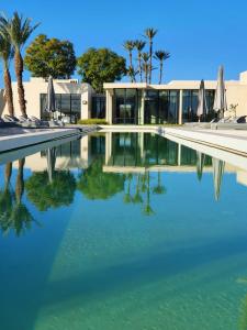 a swimming pool in front of a house with trees and a building at Bakkal Farm Agrolodge in Marrakech