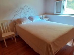 a bedroom with a bed and a chair and a window at Casa do sanguinho in Faial da Terra