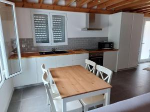 een keuken met een houten tafel en witte stoelen bij Casa do sanguinho in Fayal da Terra