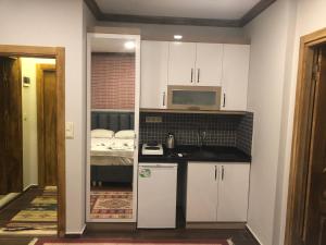 uma cozinha com armários brancos, um lavatório e uma cama em DIMBIL APART em Istambul