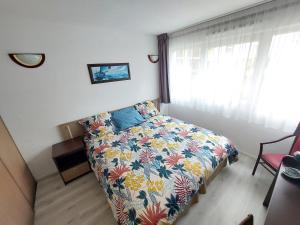 1 dormitorio con 1 cama con colcha de flores y ventana en Studio meublé avec parking idéalement placé, en Idron