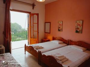 two beds in a room with a large window at Kandilari Apartments in Kokkino Nero