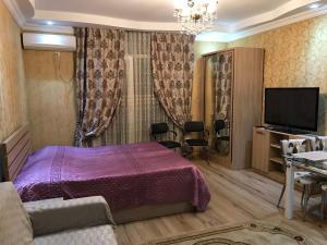 a bedroom with a purple bed and a flat screen tv at Orbi Towers Batumi in Batumi