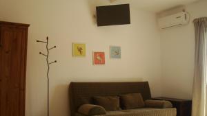 a living room with a couch and a tv on the wall at Merlot Village Rental Apartments in Kariá