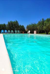 une piscine avec des chaises bleues en arrière-plan dans l'établissement Le case di Anna e Carla, à Rilievo