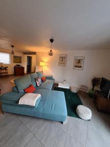 ein Wohnzimmer mit einem blauen Sofa in einem Zimmer in der Unterkunft Agréable appartement avec Spa proche de la forêt in Bréchaumont