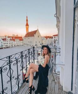 eine Frau auf einem Balkon mit Stadtblick in der Unterkunft Historic Residence Apartments at Old Town in Tallinn