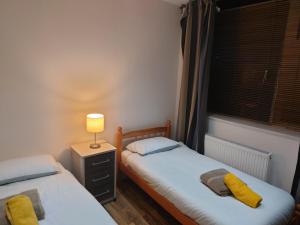 two beds in a room with a lamp and a window at City Sparrow Nest -12W in London