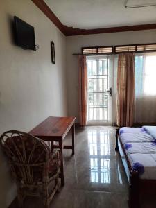 sala de estar con cama, mesa y TV en Airport Side Hotel Entebbe en Entebbe