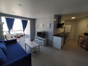 een woonkamer met een blauwe bank en een keuken bij VIVE BENALMÁDENA APARTAMENTO DIANA 604, playa y puerto a 200 metros in Benalmádena